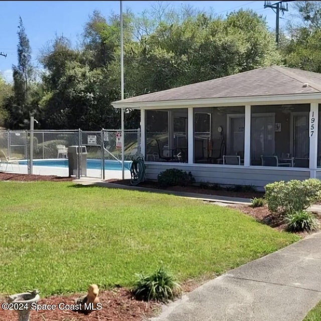 exterior space with a fenced in pool, fence, a yard, and a sunroom