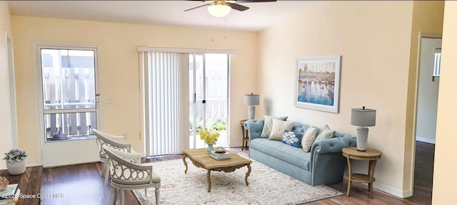 living area featuring baseboards, ceiling fan, and wood finished floors