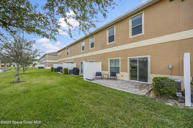 rear view of property featuring a lawn and central air condition unit