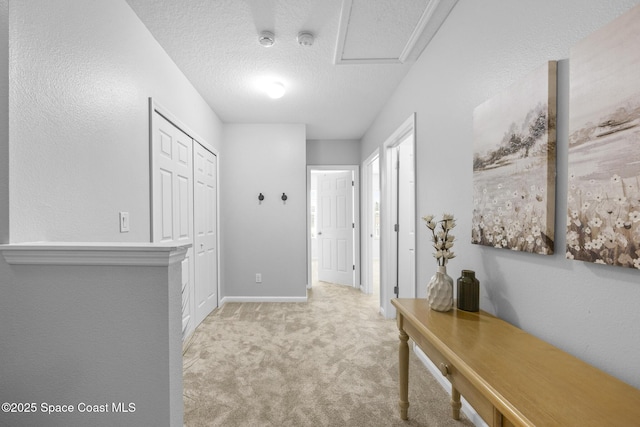 hall featuring light carpet and a textured ceiling