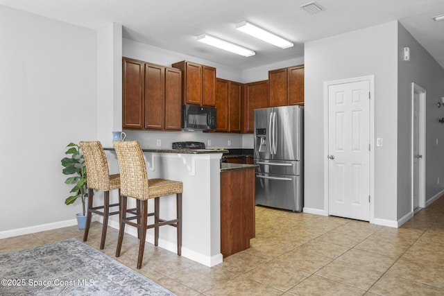 kitchen with a breakfast bar area, kitchen peninsula, stainless steel fridge with ice dispenser, and light tile patterned floors