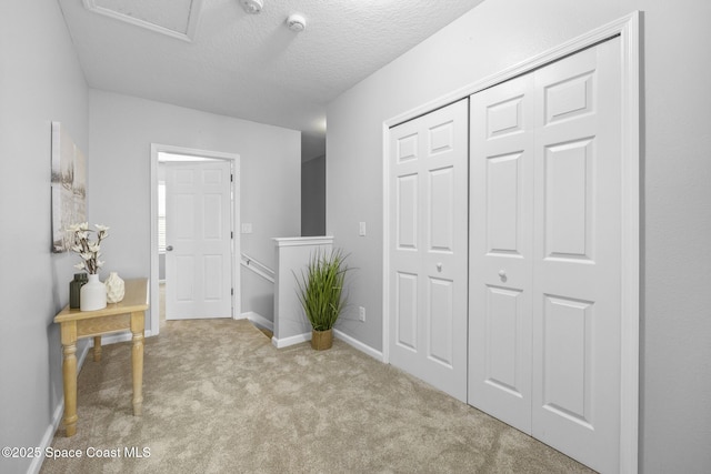 hallway featuring light carpet and a textured ceiling