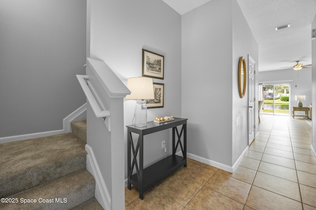 stairs featuring ceiling fan, tile patterned flooring, and a textured ceiling