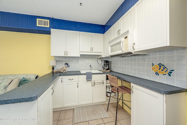 kitchen featuring white cabinetry, sink, and light tile patterned floors