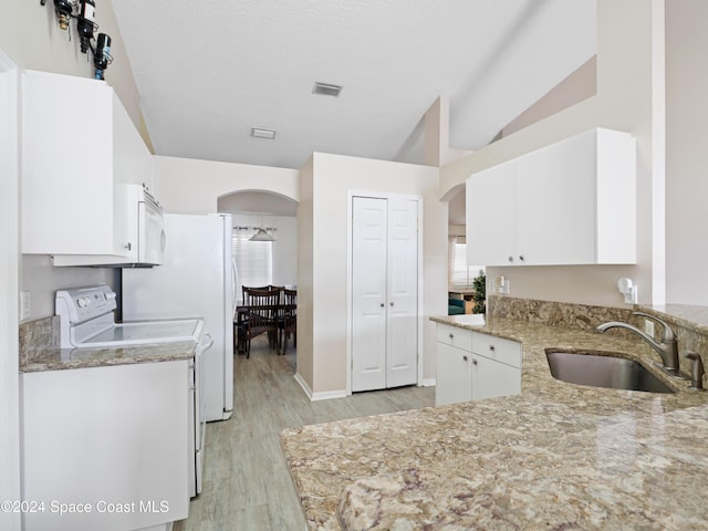 kitchen featuring white cabinetry, sink, light stone countertops, vaulted ceiling, and white appliances