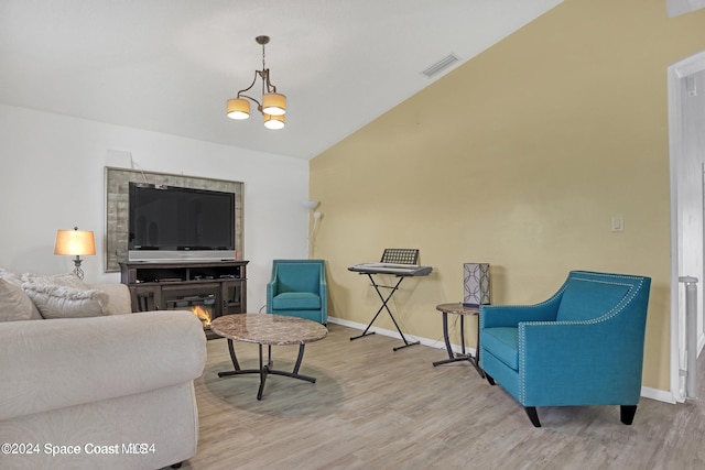 living room featuring light hardwood / wood-style floors, lofted ceiling, and an inviting chandelier