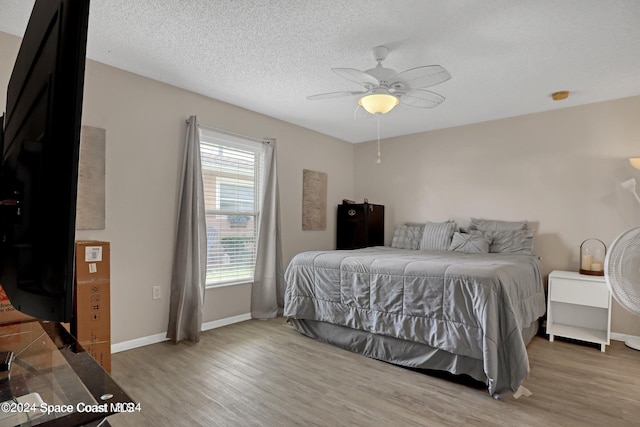 bedroom with multiple windows, ceiling fan, wood-type flooring, and a textured ceiling