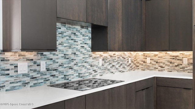 kitchen featuring backsplash, black electric cooktop, and dark brown cabinets