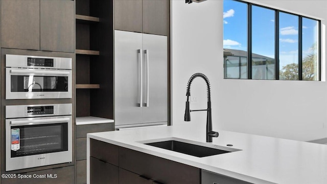 kitchen with dark brown cabinetry, sink, and appliances with stainless steel finishes