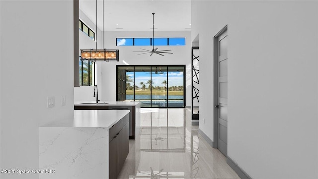 kitchen featuring pendant lighting, dishwasher, sink, ceiling fan, and light stone counters