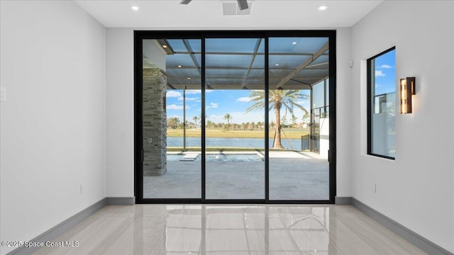 doorway to outside featuring ceiling fan, a water view, a healthy amount of sunlight, and a wall of windows