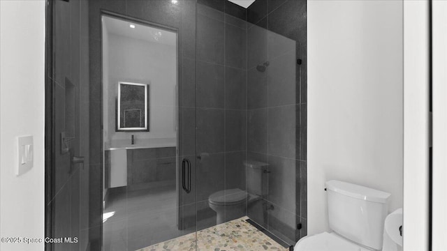 bathroom with tile patterned floors, toilet, and a shower with door