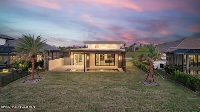 back house at dusk with a patio area and a yard