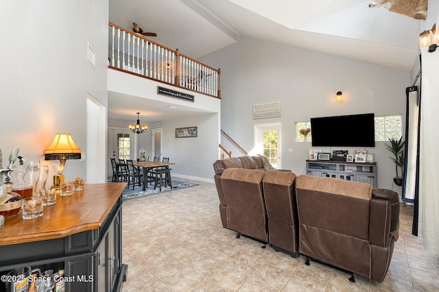 tiled living room featuring ceiling fan with notable chandelier and high vaulted ceiling