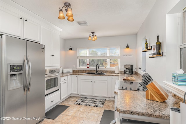 kitchen featuring white cabinetry, sink, stainless steel appliances, a chandelier, and light tile patterned floors