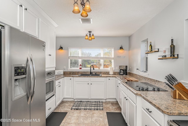 kitchen featuring sink, light tile patterned floors, a textured ceiling, white cabinets, and appliances with stainless steel finishes