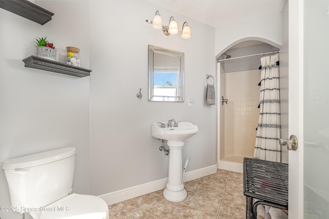 bathroom with tile patterned floors, a shower with curtain, toilet, and a textured ceiling