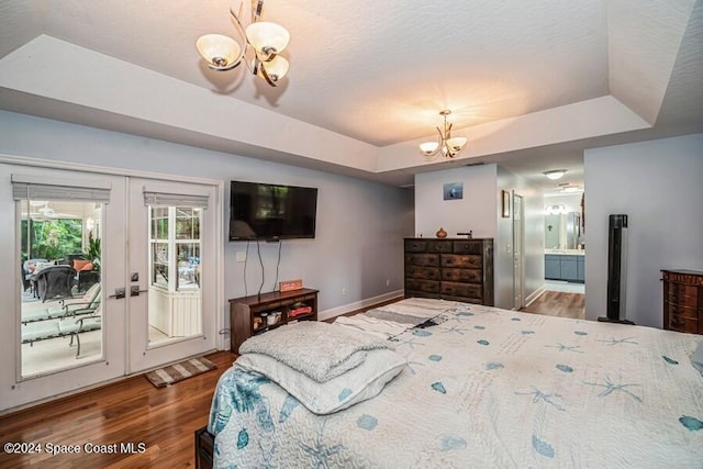 bedroom with access to exterior, french doors, an inviting chandelier, a raised ceiling, and hardwood / wood-style flooring