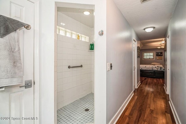 bathroom with tiled shower, hardwood / wood-style floors, and a textured ceiling