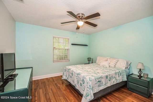 bedroom with ceiling fan, dark hardwood / wood-style floors, and a textured ceiling