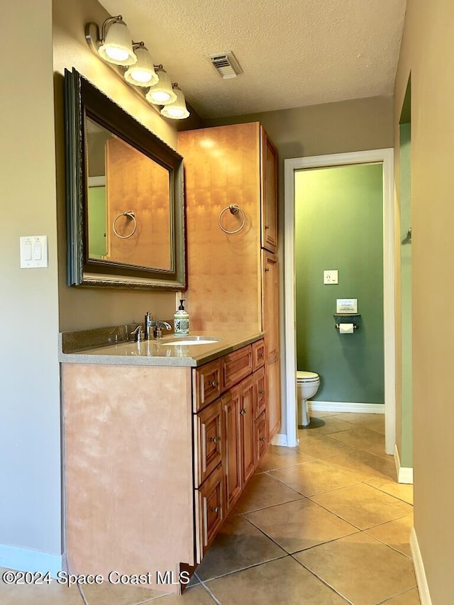 bathroom with tile patterned flooring, vanity, a textured ceiling, and toilet