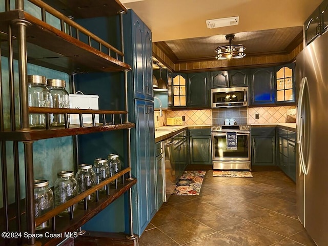 bar with tasteful backsplash, sink, dark tile patterned flooring, and appliances with stainless steel finishes