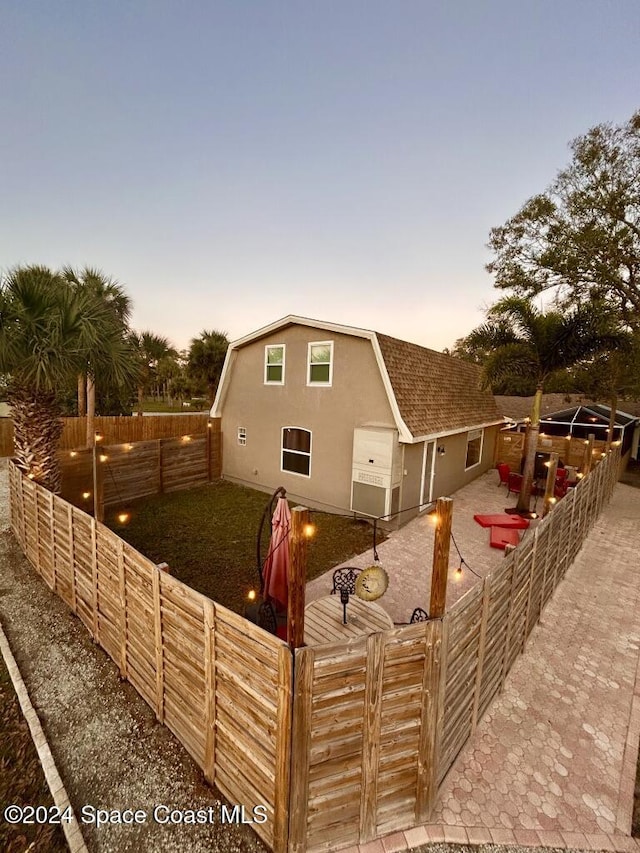 back house at dusk with a patio area