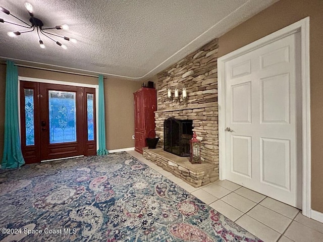 unfurnished living room with a fireplace, light tile patterned floors, a textured ceiling, and an inviting chandelier