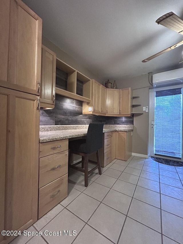 kitchen with decorative backsplash, light brown cabinetry, a wall mounted AC, light tile patterned floors, and built in desk