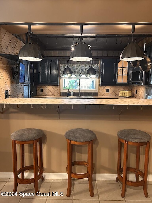 kitchen featuring a kitchen breakfast bar, light tile patterned floors, and sink