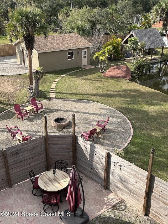 view of yard featuring a fire pit, a patio area, and a water view