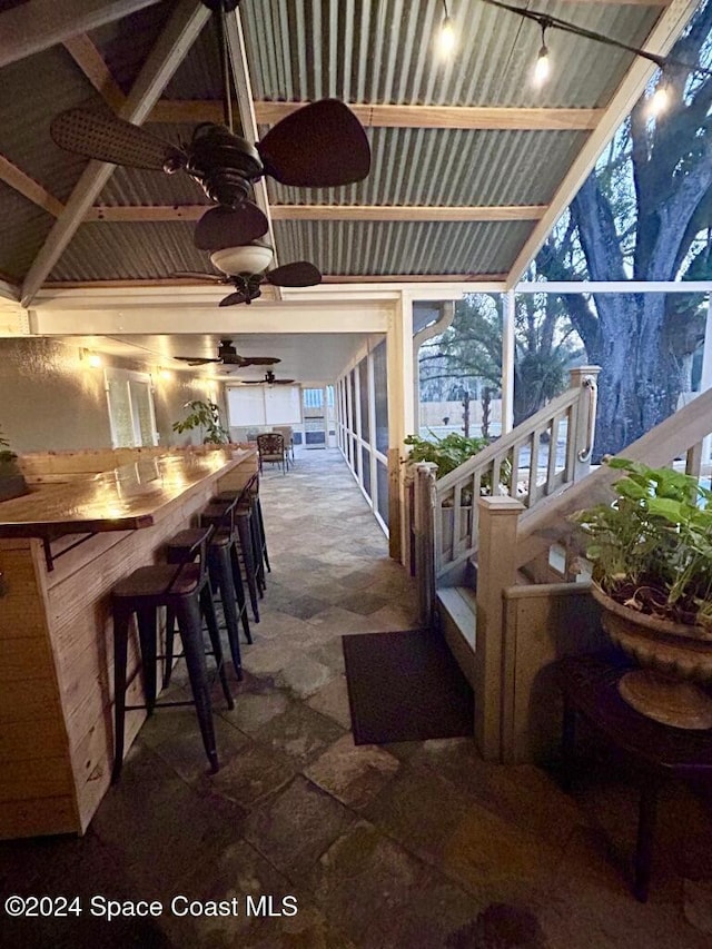 view of patio featuring ceiling fan and a bar