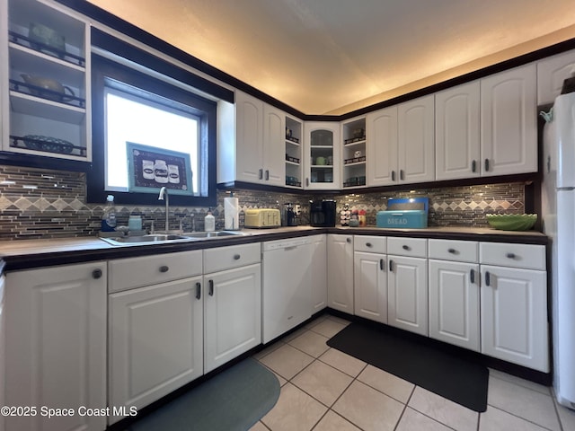 kitchen featuring backsplash, white appliances, sink, white cabinetry, and light tile patterned flooring