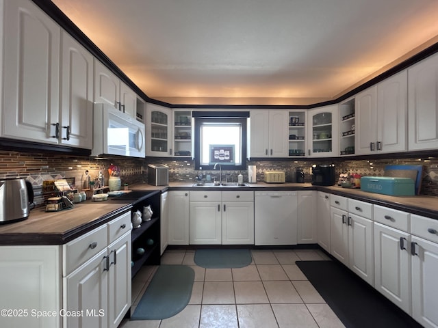 kitchen featuring white cabinetry, sink, light tile patterned floors, and white appliances