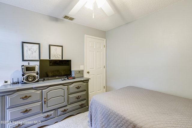 carpeted bedroom featuring a textured ceiling and ceiling fan