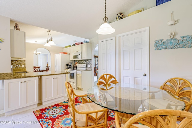 tiled dining space featuring sink, lofted ceiling, and a chandelier