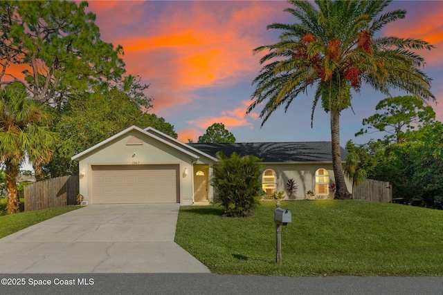 ranch-style home featuring a garage and a lawn