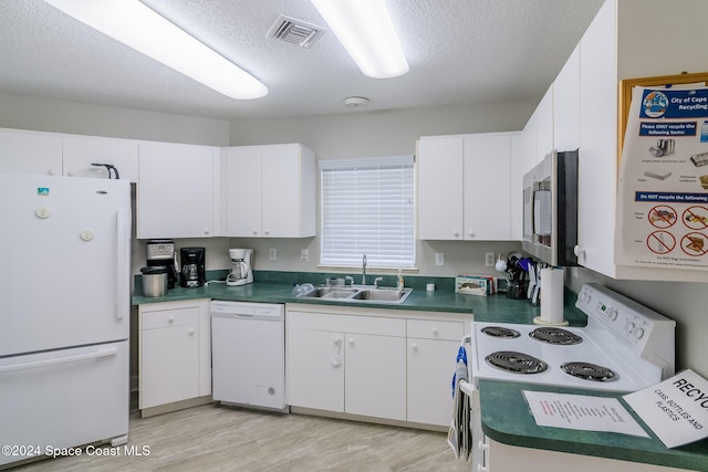 601 Shorewood Dr Unit 402, Cape Canaveral, FL 32920 - kitchen with white appliances, white cabinets, a textured ceiling, light wood-style flooring, and dark countertops