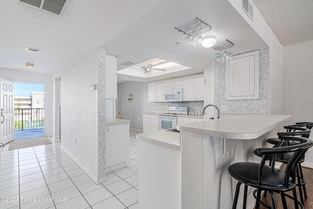 kitchen with white cabinets, white appliances, kitchen peninsula, and a breakfast bar