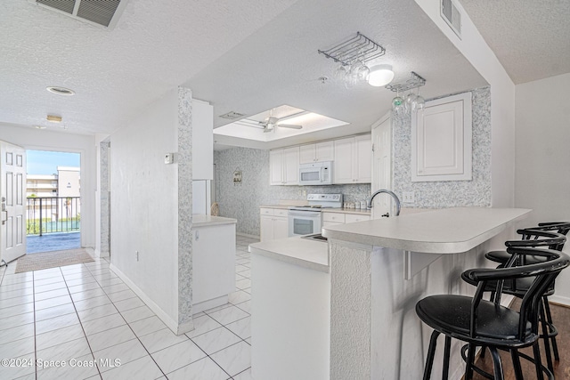 601 Shorewood Dr Unit 402, Cape Canaveral, FL 32920 - kitchen with white appliances, a textured ceiling, a peninsula, light countertops, and light tile patterned floors