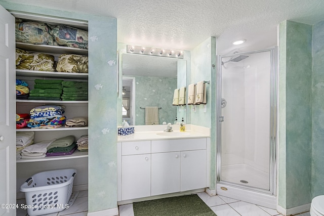 bathroom with tile patterned flooring, vanity, a textured ceiling, and walk in shower