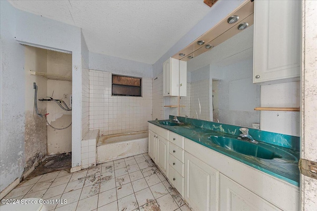 bathroom with vanity, a tile shower, and a textured ceiling