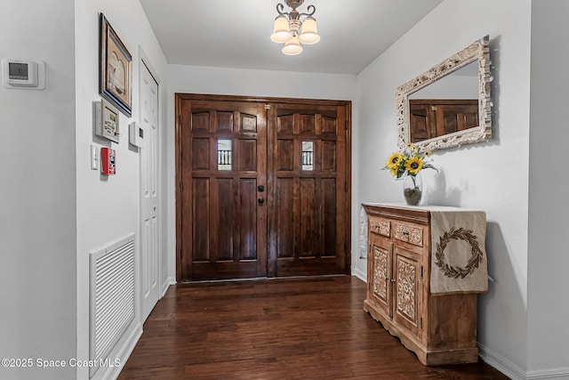 entryway featuring dark wood-type flooring and an inviting chandelier