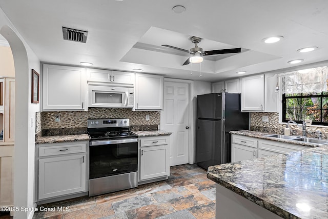 kitchen with sink, a tray ceiling, refrigerator, and electric stove