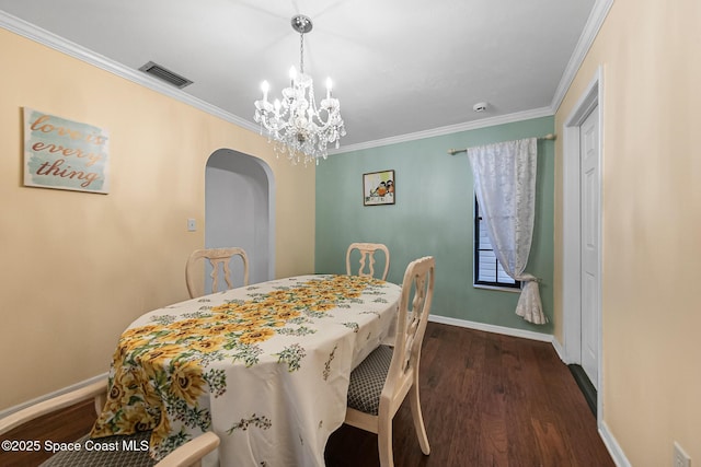 dining area with ornamental molding, dark wood-type flooring, and an inviting chandelier