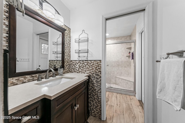 bathroom featuring a shower with door, vanity, and tile walls