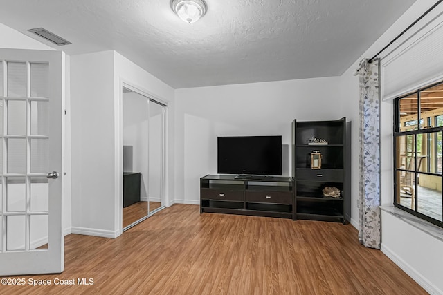 unfurnished living room featuring a textured ceiling and light hardwood / wood-style flooring