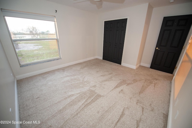 unfurnished bedroom with ceiling fan, light colored carpet, and a closet