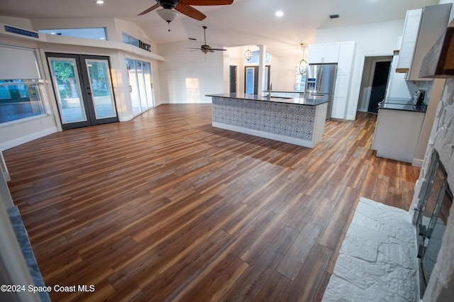 unfurnished living room with hardwood / wood-style floors, ceiling fan, french doors, sink, and lofted ceiling