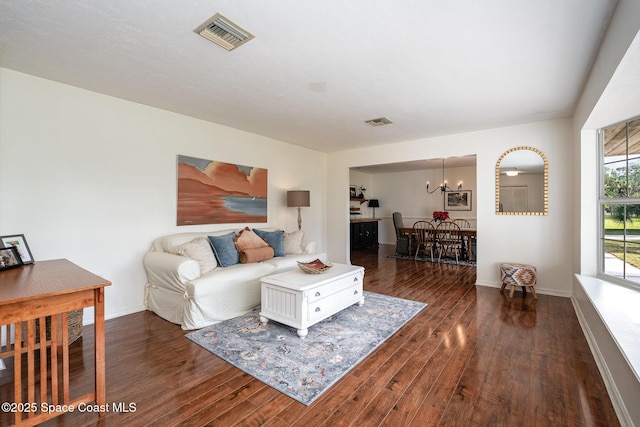 living room featuring dark wood-type flooring and an inviting chandelier